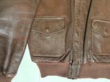 brown leather jacket with zippers and pockets on a white surface
