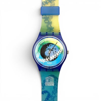 a close up of a watch on a white surface with a blue band