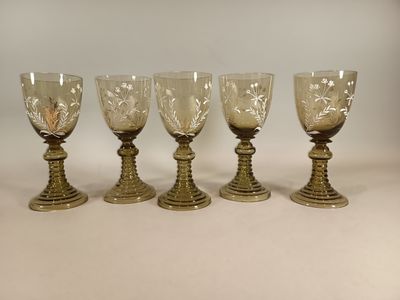 quatre verres à pied sont alignés sur une surface blanche