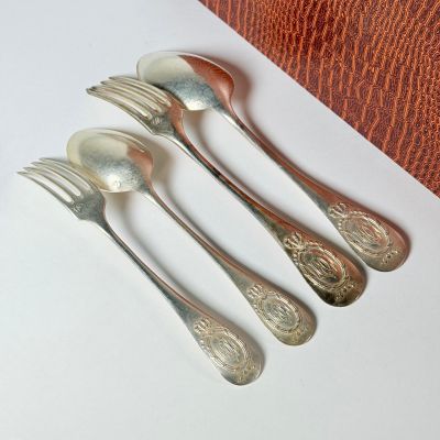 quatre cuillères et une fourchette en argent sur une surface blanche