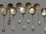 six silver spoons and two silver spoons on a gray surface