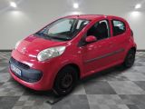 La petite voiture rouge est garée dans le garage, sur le sol à damier.