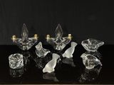 six bougeoirs en verre transparent posés sur une table noire, sur fond noir