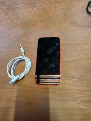 a cell phone sitting on a table with a charger attached to it