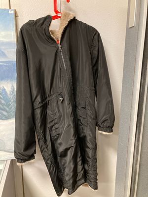 une veste noire accrochée à un mur, avec un tableau en arrière-plan