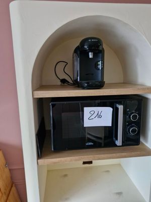 un micro-ondes posé sur une étagère dans un coin de la pièce