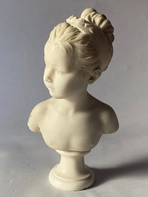 un buste blanc représentant une jeune fille avec un chignon sur la tête