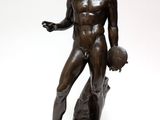bronze statue of a man holding a ball on a white background