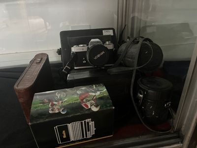 une photo montrant une valise, un appareil photo et d'autres objets dans une vitrine