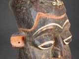 un gros plan d'un masque en bois sur fond gris
