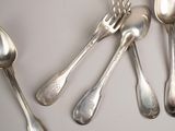 five silver spoons and two silver spoons on a table