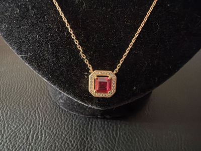 un gros plan d'un collier porté par un mannequin, orné d'une pierre rouge