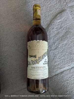 une bouteille de vin posée sur un lit, à côté d'une autre bouteille de vin