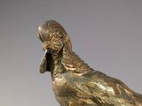 bronze statue of a bird on a pedestal with a gray background