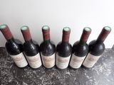 six bottles of wine are lined up on a table