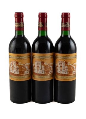 trois bouteilles de vin rouge posées l'une à côté de l'autre sur une surface blanche