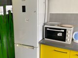a refrigerator and a microwave in a kitchen with yellow cabinets