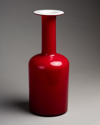 un vase rouge avec un couvercle blanc posé sur une surface grise