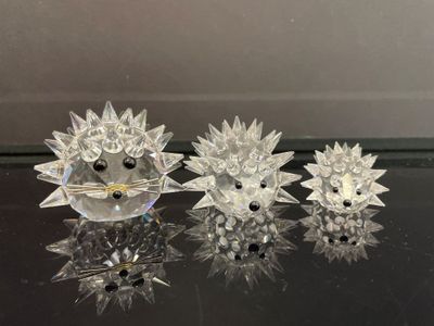trois figurines de hérissons en cristal posées sur une table