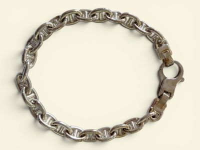 a silver bracelet with a clasp on a white surface