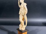 carved ivory figurine of a woman holding a bird on a pedestal