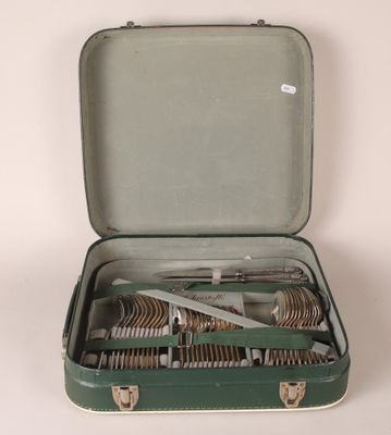 a green suitcase with silverware in it on a white surface