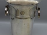 an antique silver plated ice bucket with two handles on a grey background