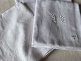 trois serviettes de table en lin blanc ornées de monogrammes brodés, posées sur un lit