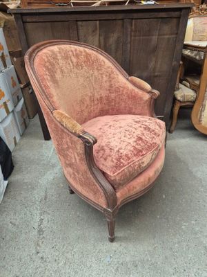 an old chair with a pink velvet upholstered and a wooden arm rest