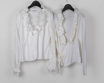 pair of white blouses hanging on a hanger against a white wall