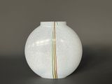 a white vase sitting on a table with a green stripe on it