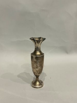 a silver vase that is sitting on a white surface