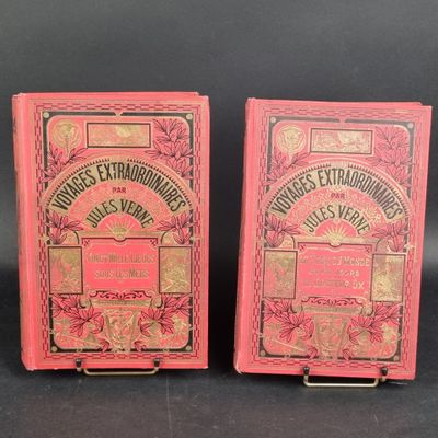 two old books are sitting side by side on a black surface