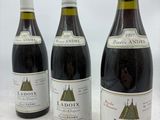 trois bouteilles de vin rouge sont alignées sur une table