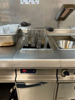 une cuisine équipée d'un évier et d'une cuisinière sur laquelle sont posées de nombreuses casseroles et poêles