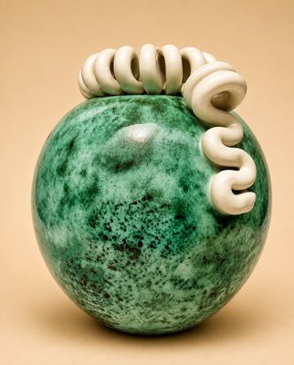 une photo d'un vase vert orné de spirales blanches