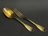 two gold spoons and a fork on a black surface