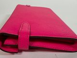 a pink leather wallet with a zipper closure