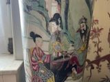 a vase with a painting on it sitting on a table