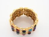 a close up of a gold bracelet with multi colored stones
