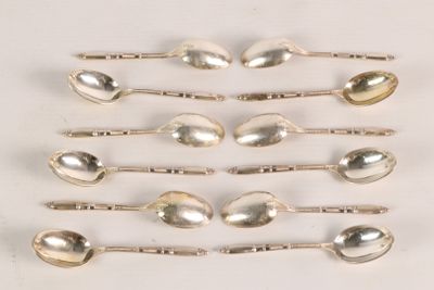 six silver spoons are lined up in a row on a white surface