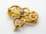a gold brooch with a pearl in the center