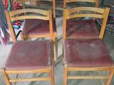 quatre chaises en bois avec des assises en cuir rouge dans une pièce