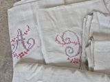 a pile of white linens with red embroiderys on them