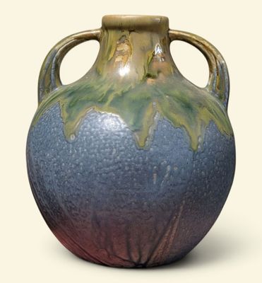 un vase bleu et vert posé sur une surface blanche