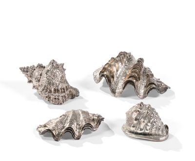 quatre coquillages argentés sont disposés sur une surface blanche