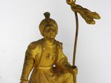 a gold statue of a man with a bird on top of a clock