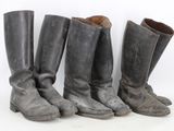 three pairs of old boots are lined up against a white wall