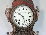 a red and gold clock with roman numerals on it