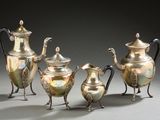 three silver teapots and two silver cups on a table